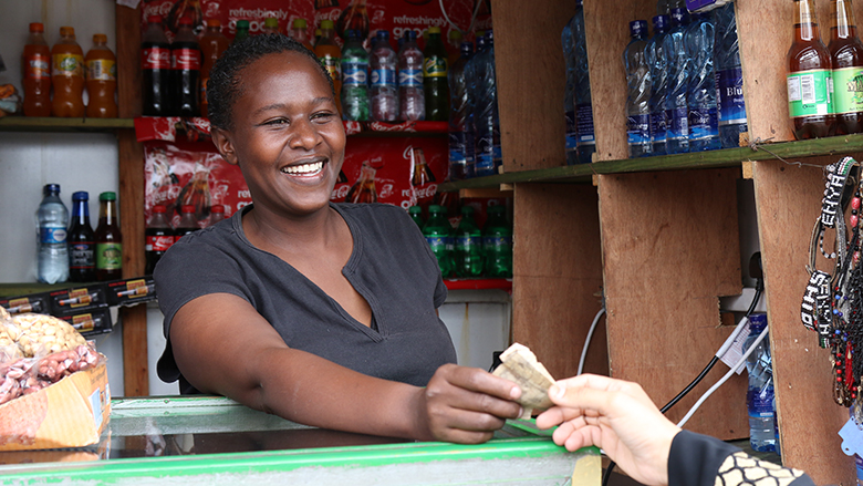 Woman shop owner in Mombasa, Kenya receives cash payment from a customer