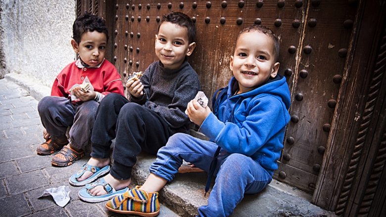  Group of small kids sitting on a step after playing in the streets of Asilah - La bionda sulla Honda | Shutterstock.com