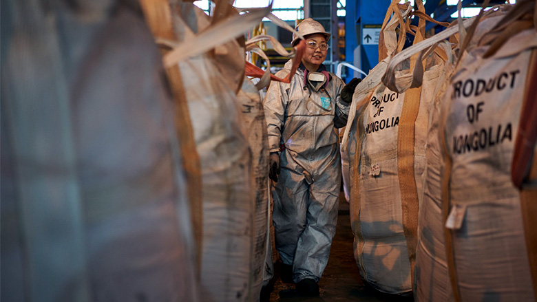 A woman employed by a copper and gold mine in Mongolia walks past bags ready for shipment