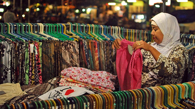 A woman examines a shirt at a market in Indonesia