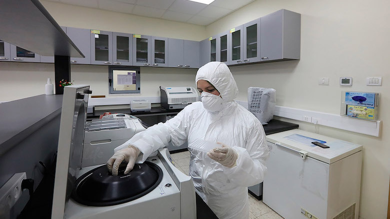 A female laboratory technician works on COVID-19 tests at the Central Public Health Laboratory in Ramallah City.