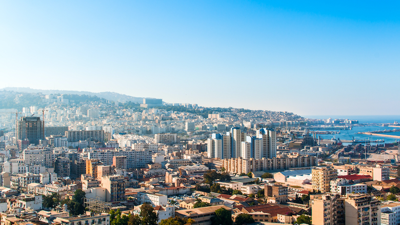 A landscape of Algiers city from Maqam Echahid monument, Algeria, appears in the distance.