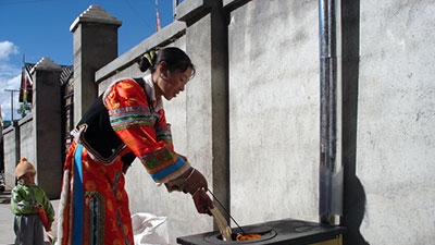 Woman in Cambodia smiles, as she uses her cookstove.