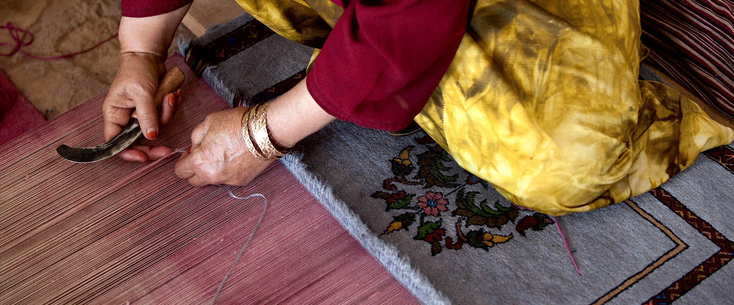 Fifty-year-old Shirin works at weaving a carpet at a carpet and silk weaving center located in the historic Herat Citadel in Afghanistan