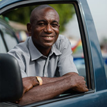 A man smiles out of the window of his van