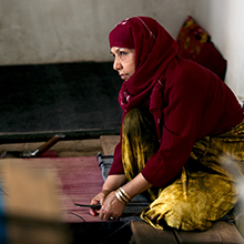 Fifty-year-old Shirin works at weaving a carpet at a carpet and silk weaving center located in the historic Herat Citadel in Afghanistan