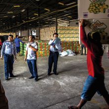 A porter carries a box of fruit through a customs warehouse at Thanaleng port in Vientiane, Laos, as customs officers work 
