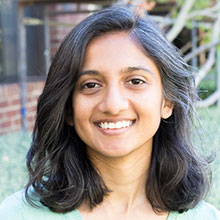 Female smiling with short black and white hair. Wearing green shirt