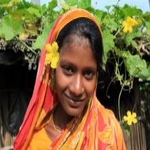Young rural lady standing in front of a floral bush in Bangladesh