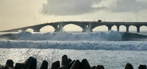 Heavy waves in front of a vehicle bridge hitting the shoreline. 
