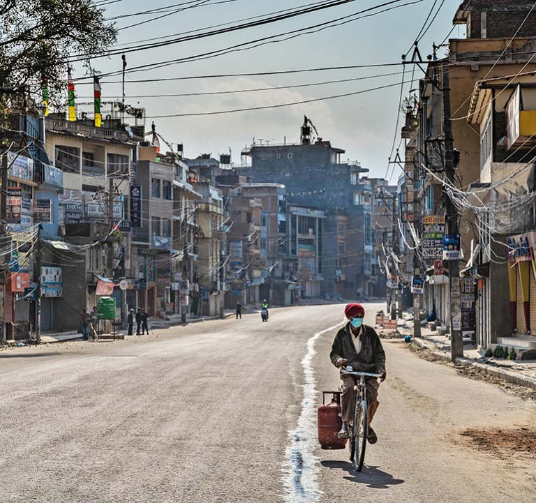 A man delivers household gas on a bicycle on an empty street in Kathmandu, Nepal, in March 2020. Photo: © Denis Dymov/Shutterstock A man delivers household gas on a bicycle on an empty street in Kathmandu, Nepal, in March 2020. Photo: © Denis Dymov/Shutterstock