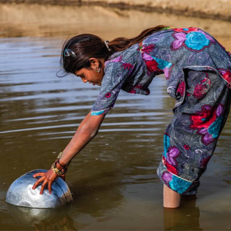 A girl gathers water from a river.