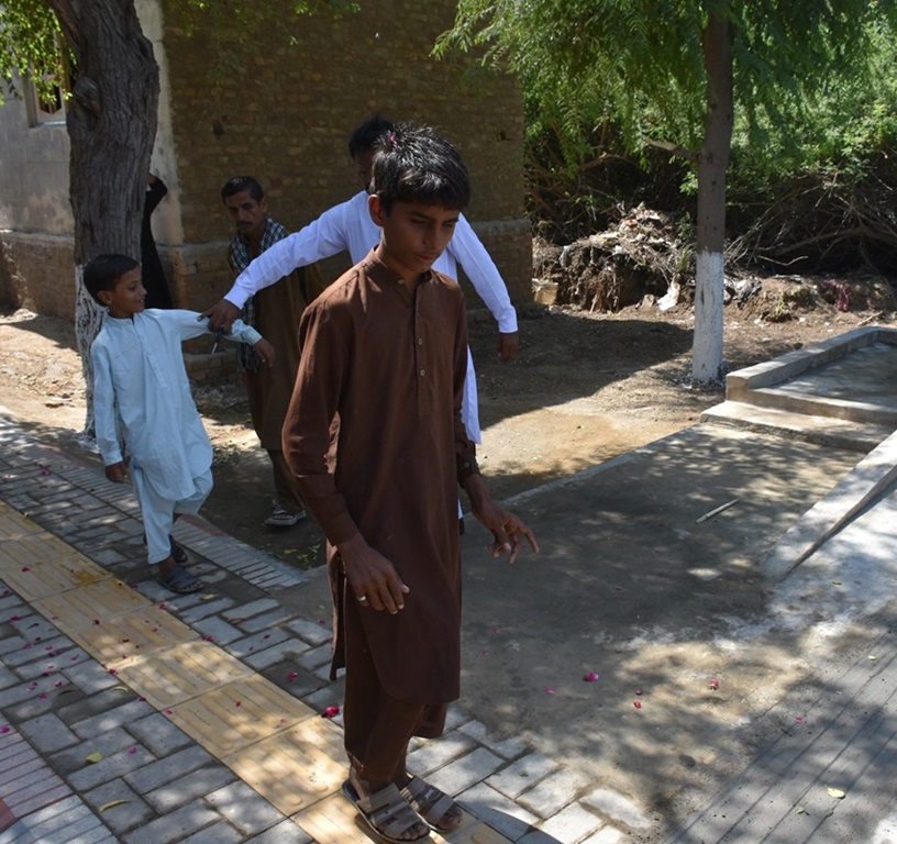 Visually impaired boy in Sindh using tactile paving to navigate village