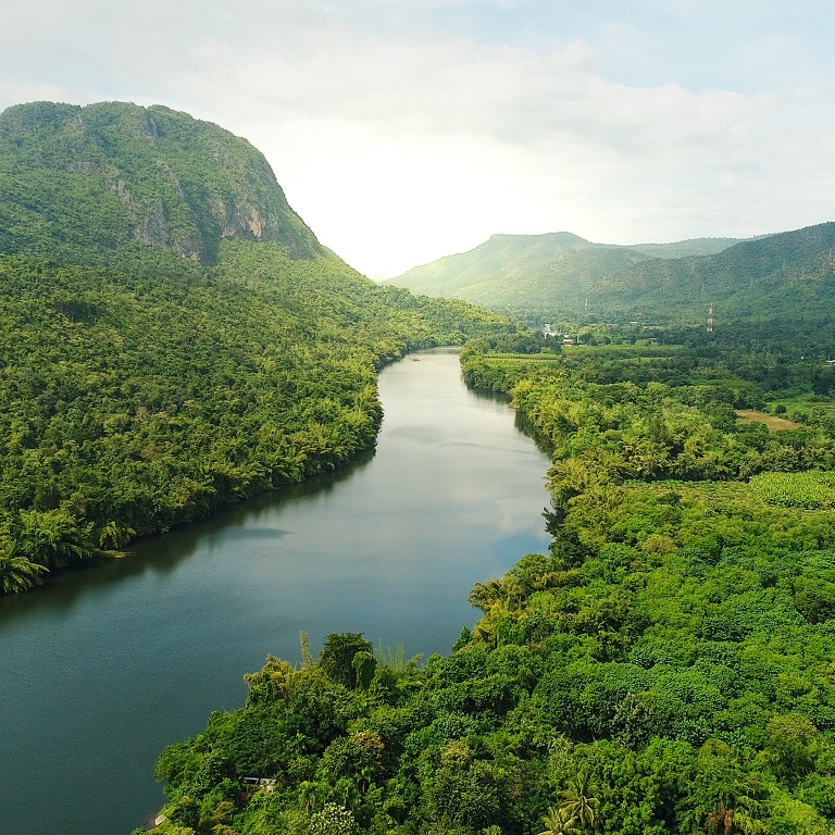Beautiful natural scenery of river in southeast Asia tropical green forest with mountains in background