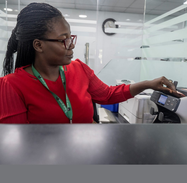 A teller at the Bank of Africa counts money at a bank window at the main branch downtown.