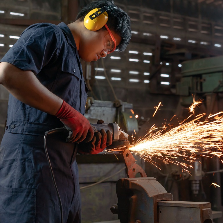 Engineer operating angle grinder hand tools in manufacturing factory