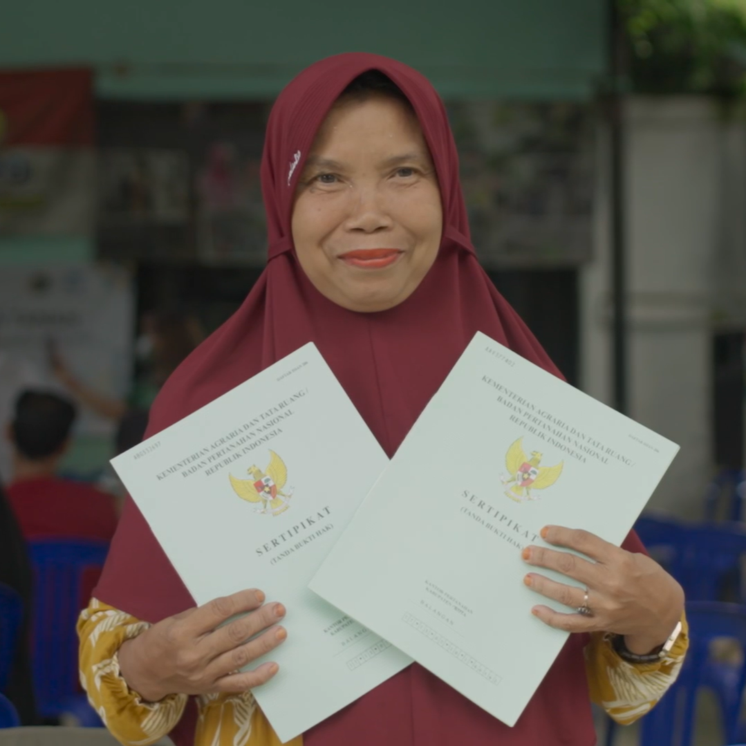 Photo of a woman with land tenure certificates in Indonesia