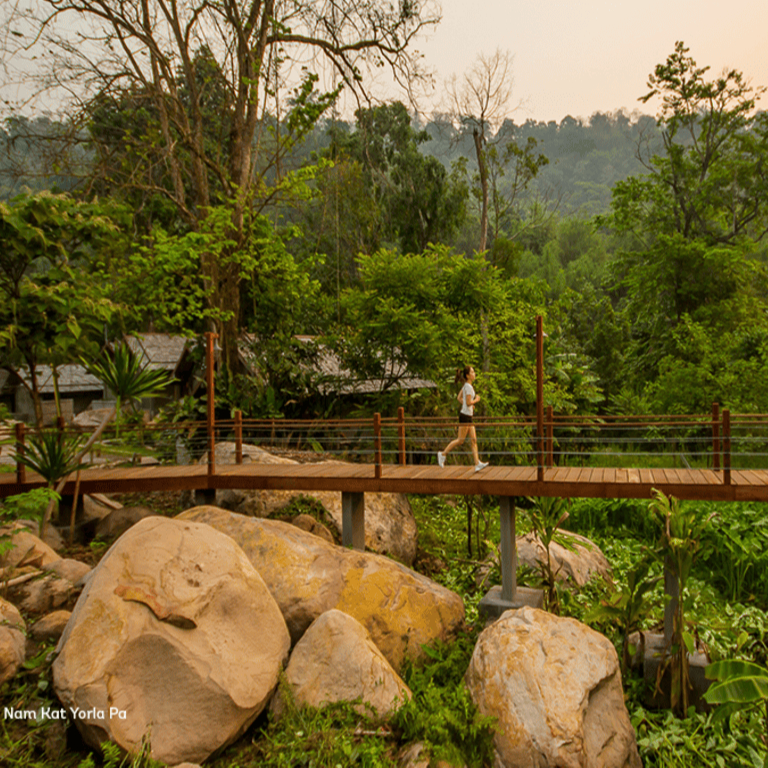 A tourist jogs across a footbridge in the forest around Nam Kat Yorapa, northern Laos 