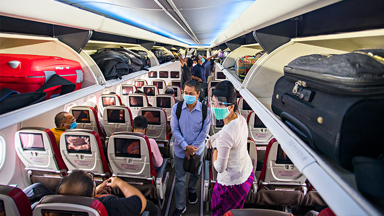 Passengers and flight attendant in Indonesia wear masks and follow health protocols in a plane cabin before flying