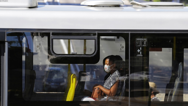 A woman is seen through the window of a public bus wearing a face mask to protect her from COVID-19 in downtown Sao Paulo, Brazil. Photo: © Nelson Antoine/Shutterstock 