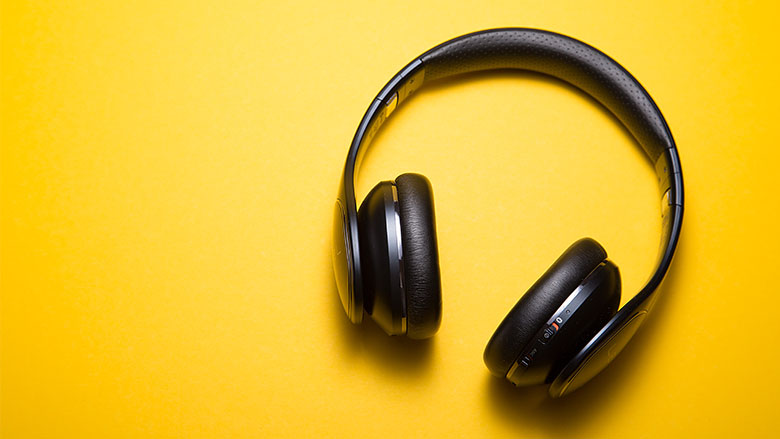 A pair of black Bluetooth headphones on a bright yellow background