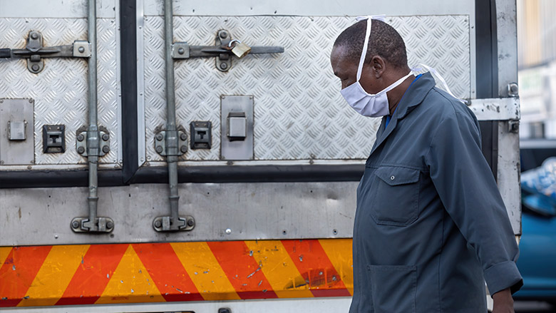 A Worker in Sub-Saharan Africa standing near a truck is seen wearing a mask 