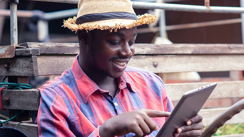An African farmer looks at a computer tablet