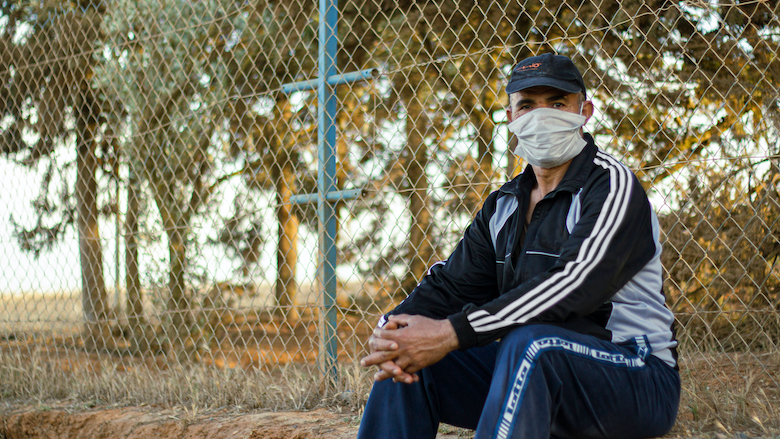 An elderly man wearing a face mask sits in a garden in Khemisset, Morocco.