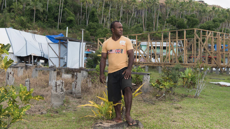 Rai Tabusoro stands at the site of his former home, current home and future home in Nabukadra, a coastal village in Ra Province, Fiji. Ra Province was one of the hardest hit by Cyclone Winston in 2016. Photo: Alana Holmberg/World Bank