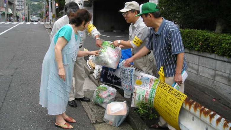 Kitakyushu city official and volunteer at a dumping site explaining trash separation to citizens
