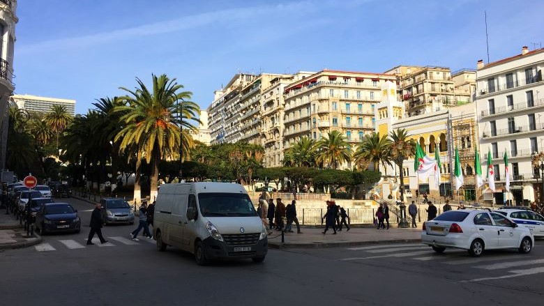 Pedestrians cross the street in a busy traffic intersection in Algeria.