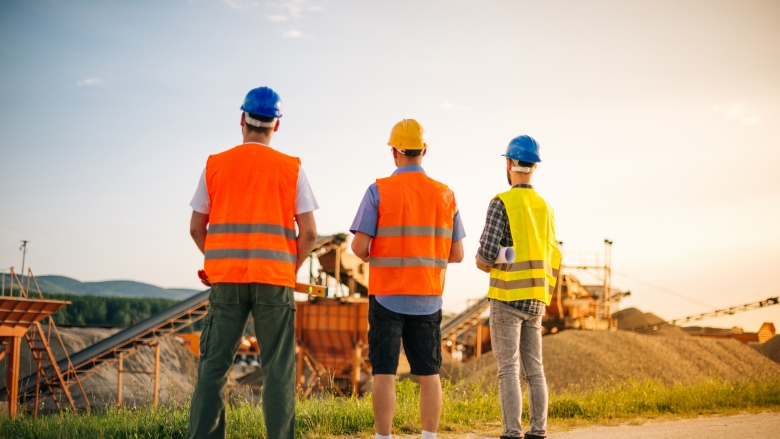 Engineers and architects on construction site, with blueprints and digital tablet. Three