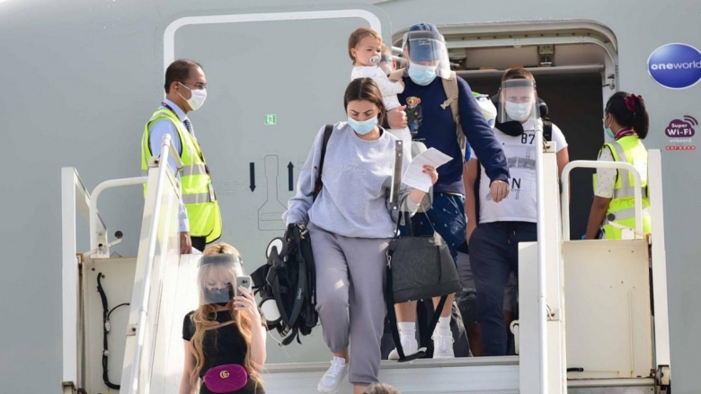 Passengers with PPE leaving a plane after landing in Maldives