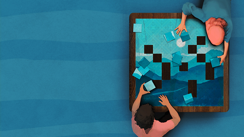 Male and female sitting in front of each other completing puzzle game