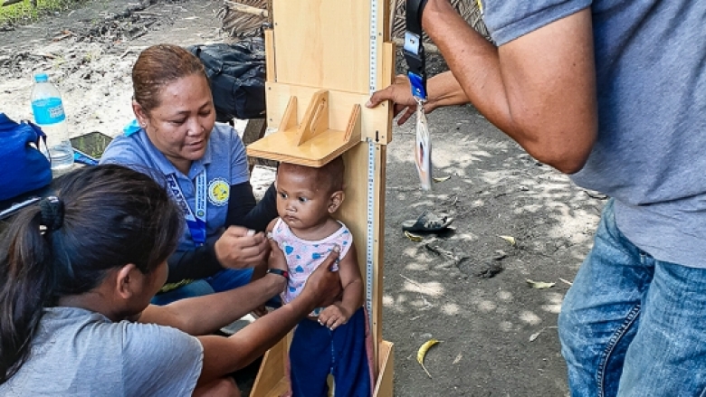 A mother helps health volunteers measure her baby’s height during a health survey in Buluan, Maguindanao. 