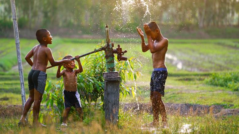 Three young boys play with a groundwater pump in Vietnam.