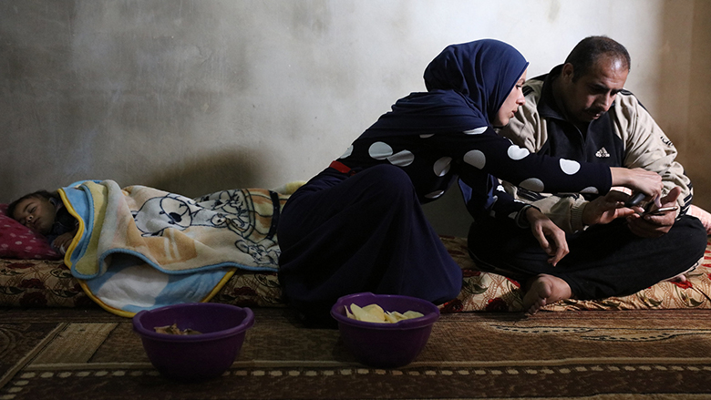 Syrian family looks at a family photo in their living room from the Haytanak slum. Photo © Dominic Chavez/World Bank