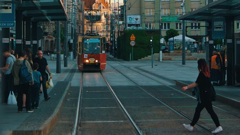 Woman crossing the street in a city, in front of an on-coming trolley