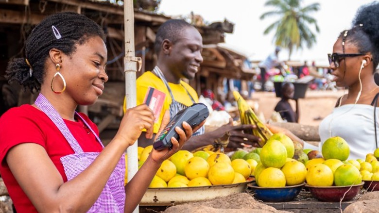 An African woman uses digital tools to process transactions for her fruit selling business at the marketplace