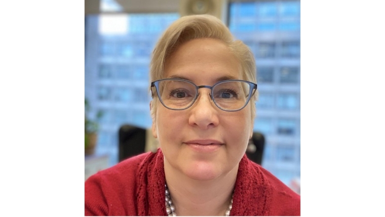 Female with short yellow hair, wearing blue eye glasses and red blouse