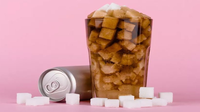 Sugar cubes in a glass next to a generic soda can