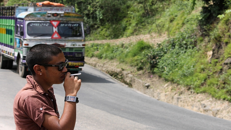 A man smoking on the side of a road