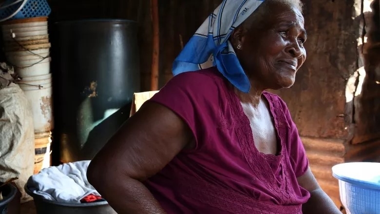 Ester Awo Bartey sits near her home in Ghana.