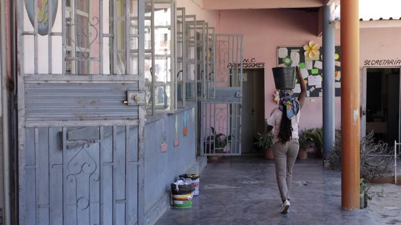 A school guard carries a bucket of water to the washrooms at Elementary School Number 98 in Lubango.