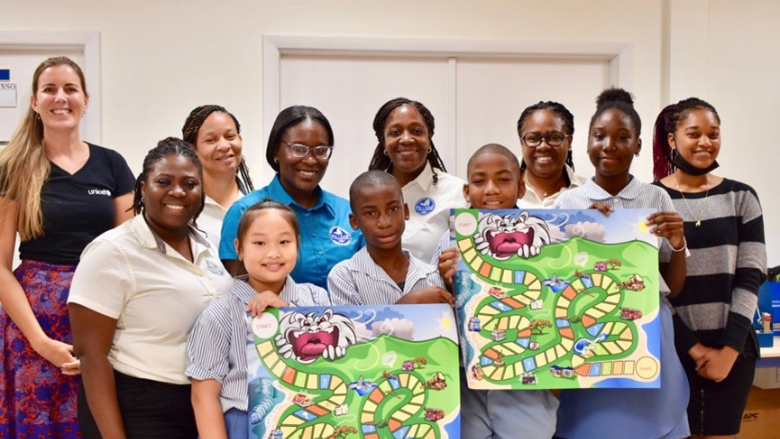 Students, teachers, and administrators at the Asha Stevens Christian Hillside School in Sint Maarten posing with board game.