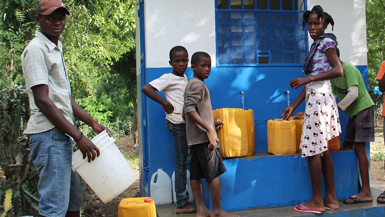 Boys and girls from Roche-à-Bateau, in Haiti, collect water from a community tap