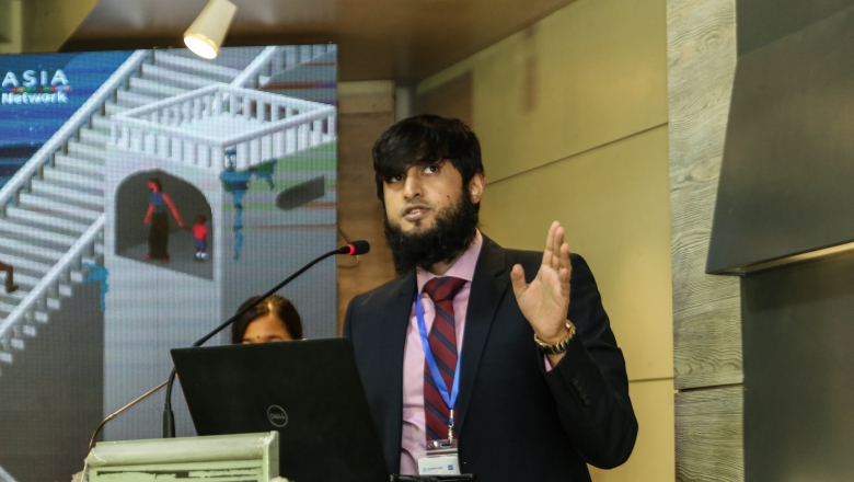 Male speaker on the podium wearing dark black suit