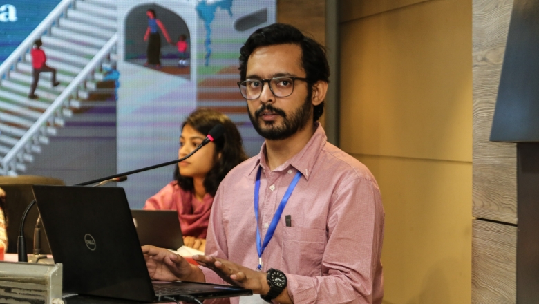 Male speaker on the podium wearing blouse and eyeglasses