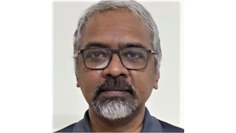 Male with white hair and goatee beard wearing eye glasses and grey blouse