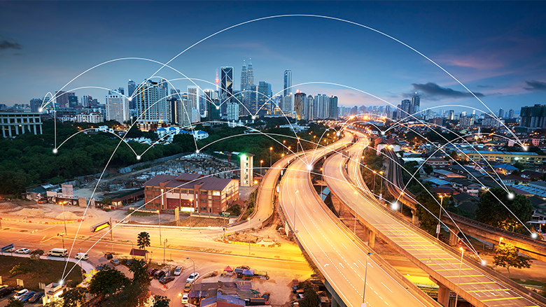 nighttime city view with digital lines connecting buildings and lighted highway 